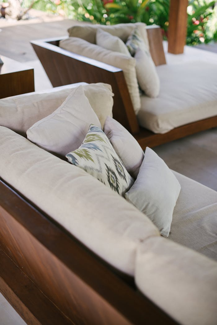 Chic outdoor lounge area featuring wooden sofas with plush cushions in a Bali villa.